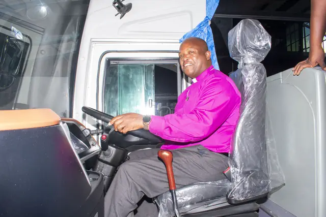 The Bishop smiling from the driver's seat of a new school bus