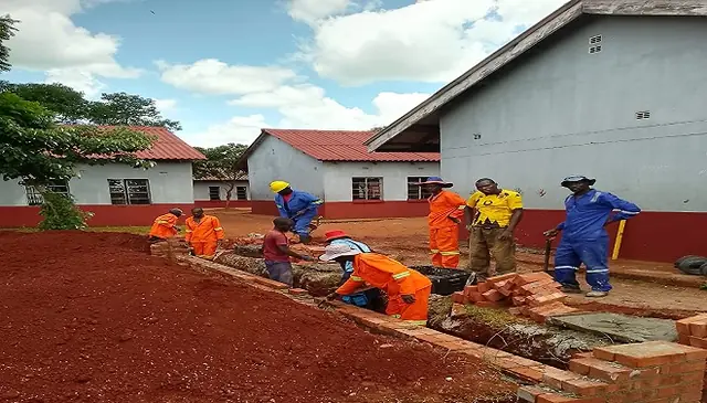 Students in overalls laying bricks for a building project