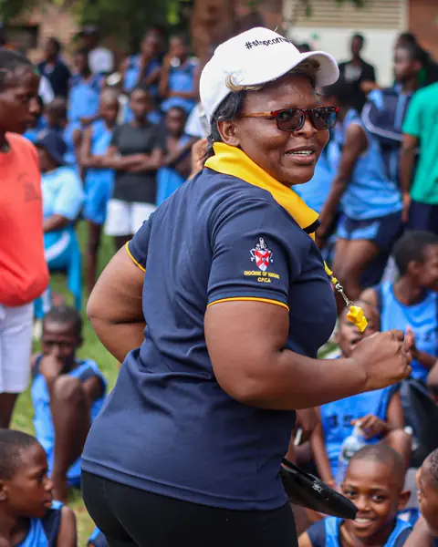 A teacher smiling with young pupils in blue uniforms during an outdoor activity
