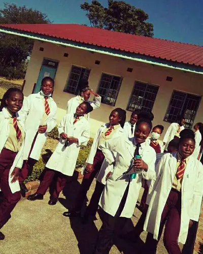 Students in white lab coats outside a science block