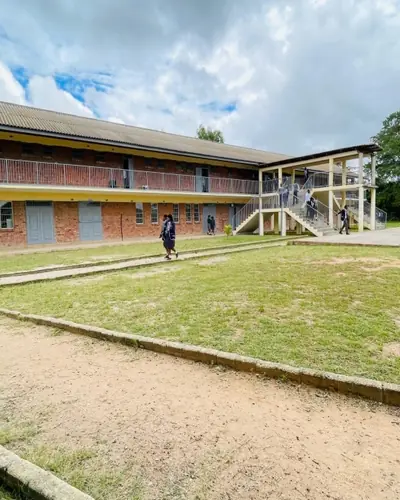 A two-storey Anglican school building beside a wide lawn