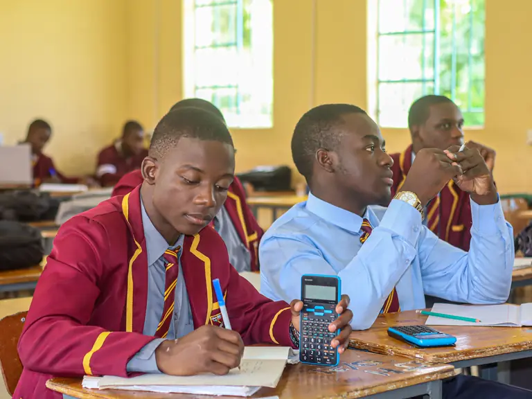 Students in maroon blazers concentrating during a maths lesson